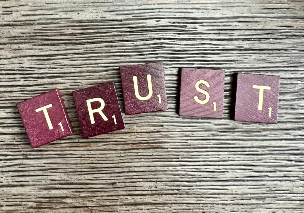 The word trust spelled out in red wood toned scrabble letters